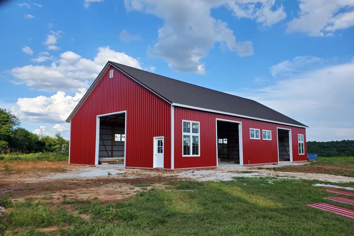 Red steel shop with white trim on open ranch land