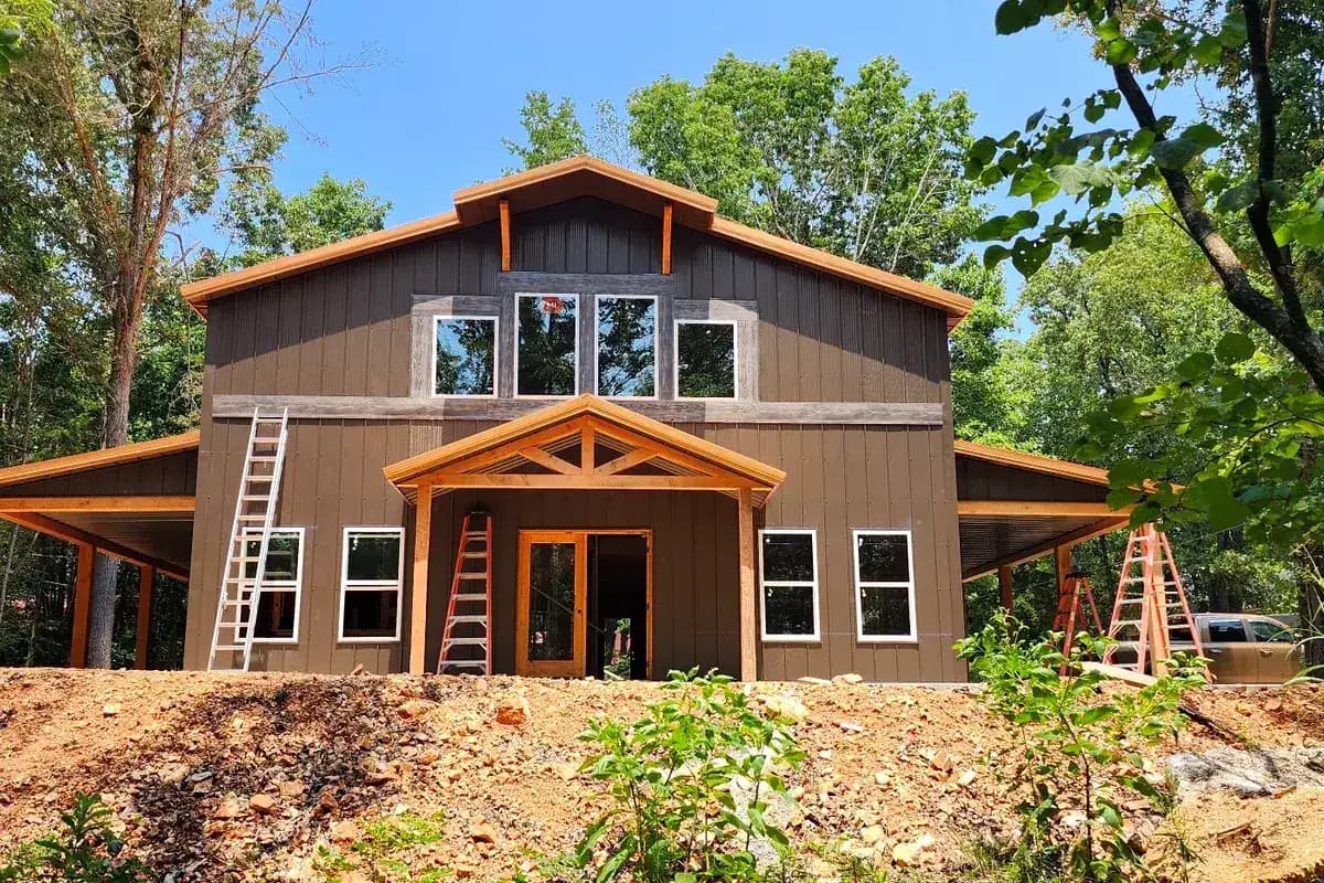 Two-story barndominium with timber frame entry and wraparound porches
