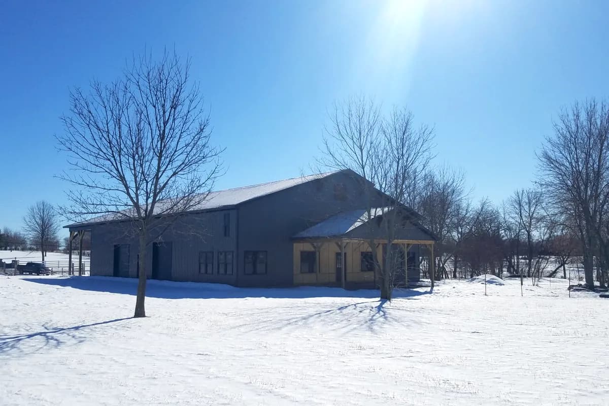 Barndominium with timber frame porch in winter