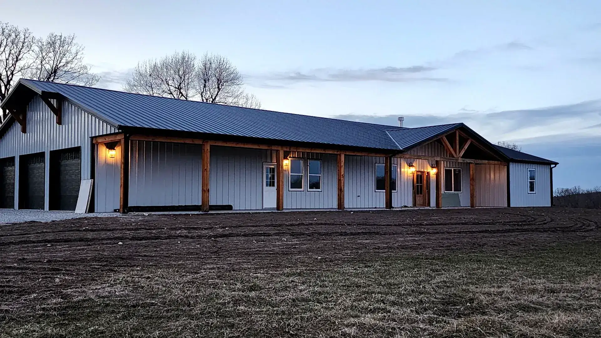 Barndominium with timber frame porch at dusk in Wyoming