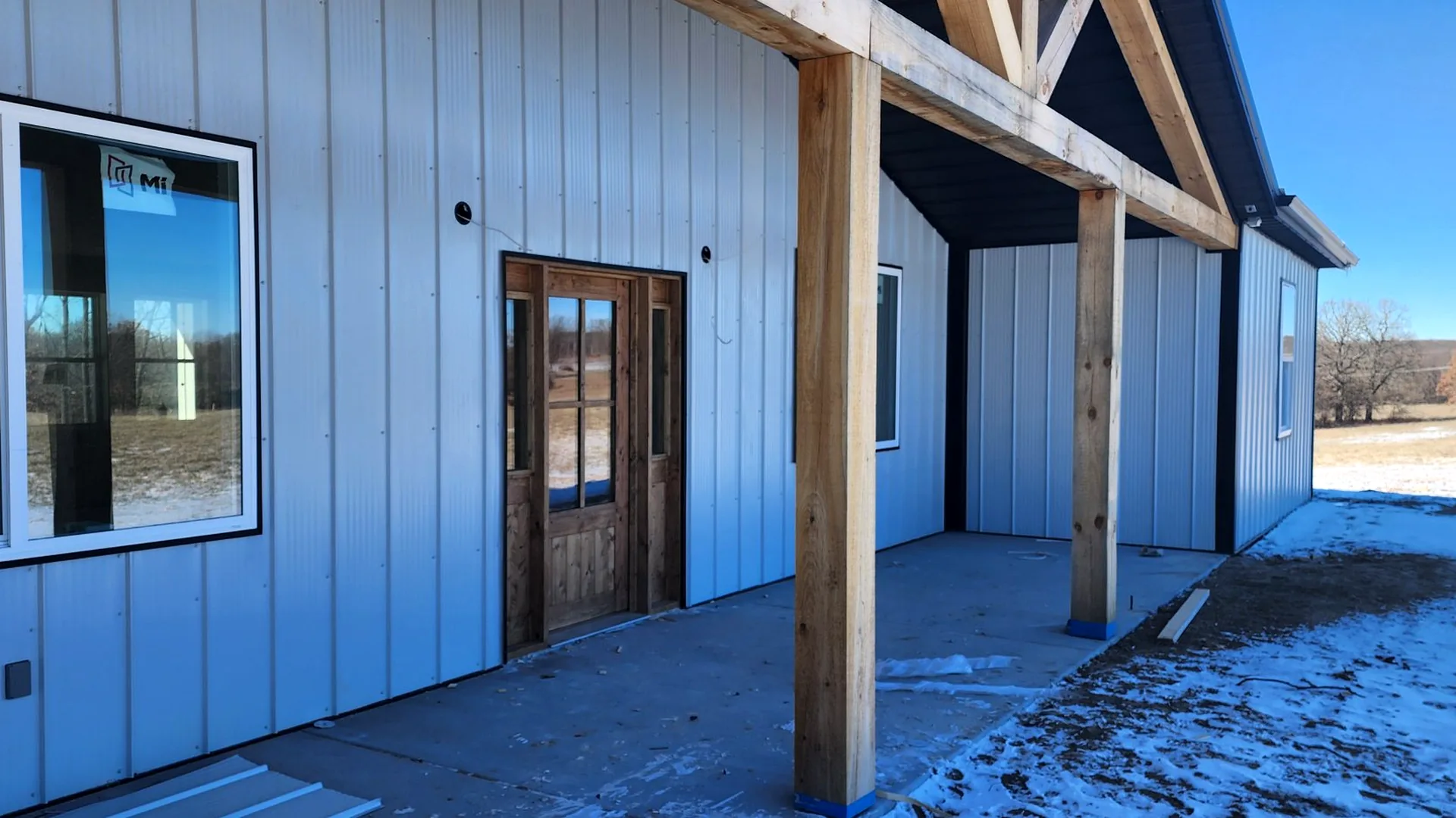 Large gray custom building with second-story balcony and timber entry