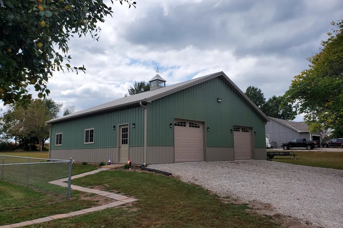 Green steel shop building with cupola and attached garage bays